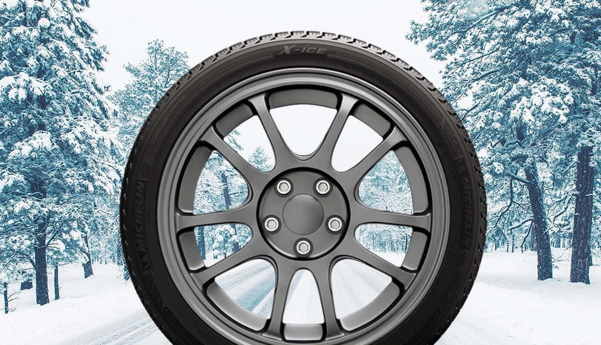 Winter Tires 桌布 壁紙 — 黑色冬季輪胎配銀色合金輪圈的近景，背景是雪覆蓋的森林。