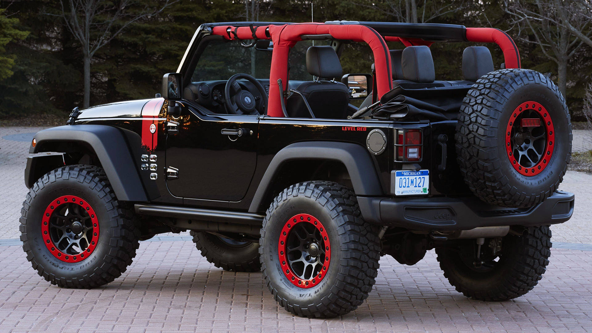 黑色Jeep Wrangler，紅色輪胎，停在磚砌車道上