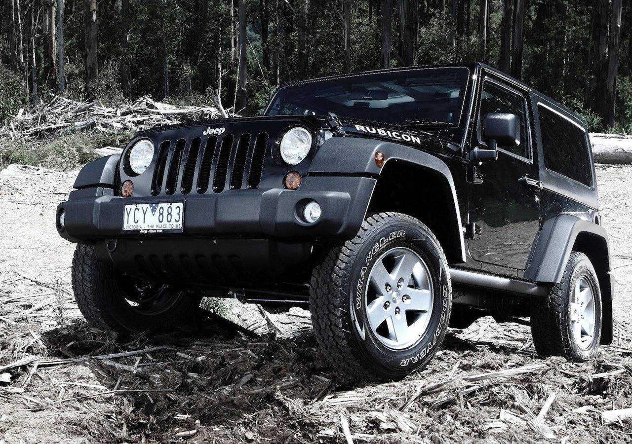 黑色Jeep Rubicon停放在有落枝和泥土的森林小徑上。