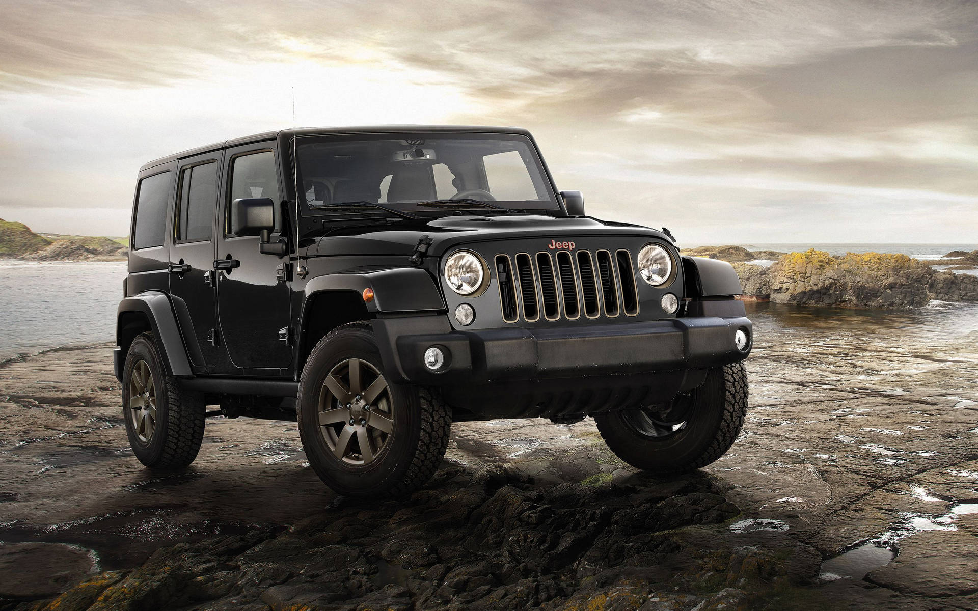 黑色Jeep Wrangler停泊在岩石海灘上，海浪拍打