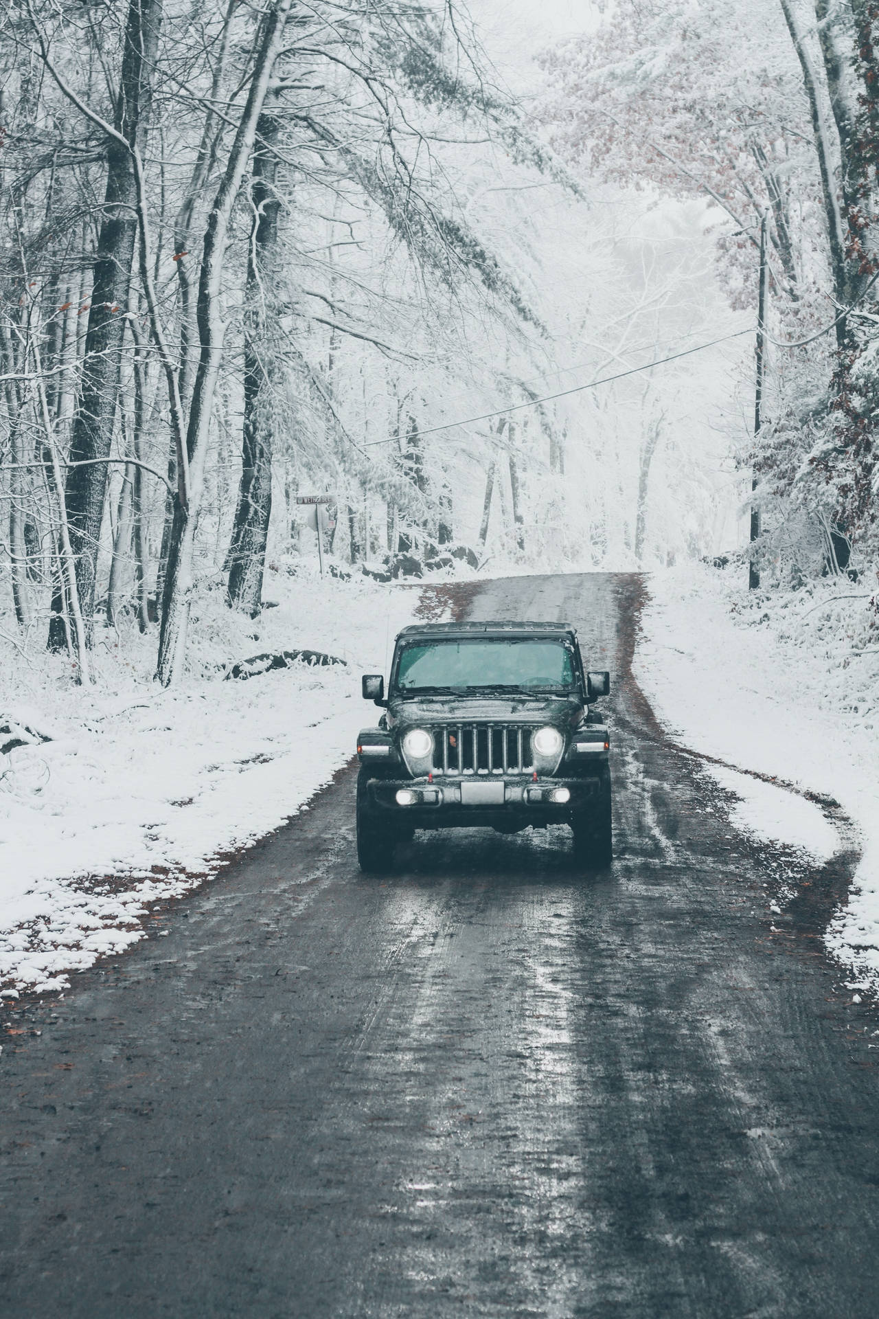 冬季積雪森林道路上的黑色吉普車
