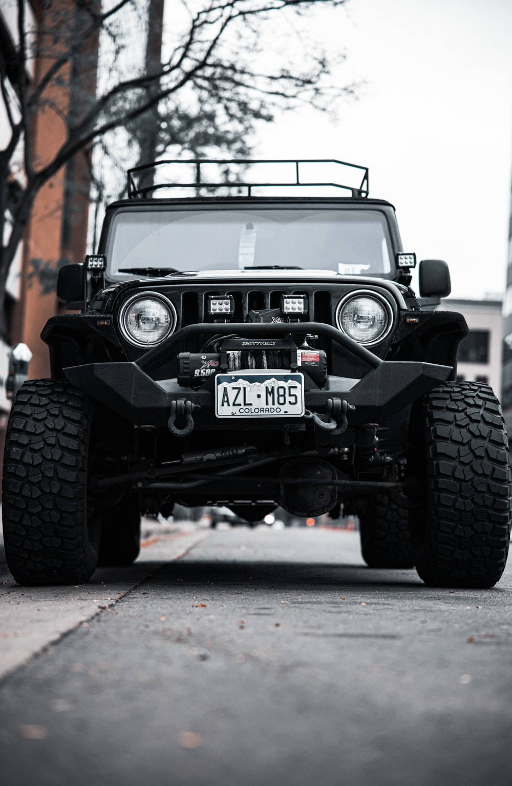 黑色改裝Jeep Wrangler停泊在城市街道上，帶有科羅拉多州車牌。