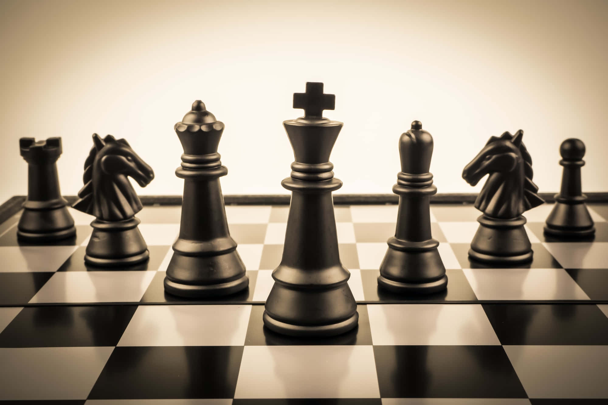 Chessboard 桌布 壁紙 — 黑色國際象棋棋子喺溫暖嘅工作室燈光下排成一排喺棋盤上。