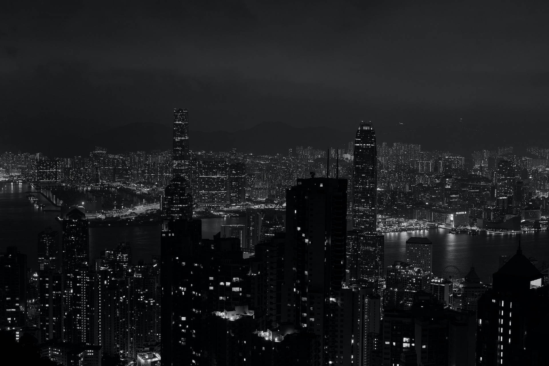 黑白夜景城市景觀，帶有明亮的建築物和一條黑暗的水道。