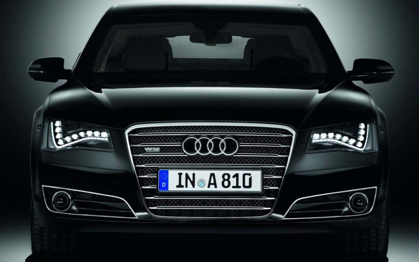 Audi S8 桌布 壁紙 — 黑色奧迪A8豪華轎車的正面視圖，配備發光LED頭燈和鍍鉻飾邊，背景為深色工作室。