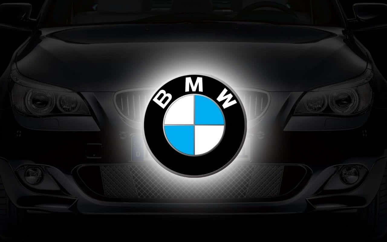 Car Logo 桌布 壁紙 — 黑色寶馬汽車的前進氣格柵發出明亮的白光，突顯出標誌性的藍白圓形標誌。