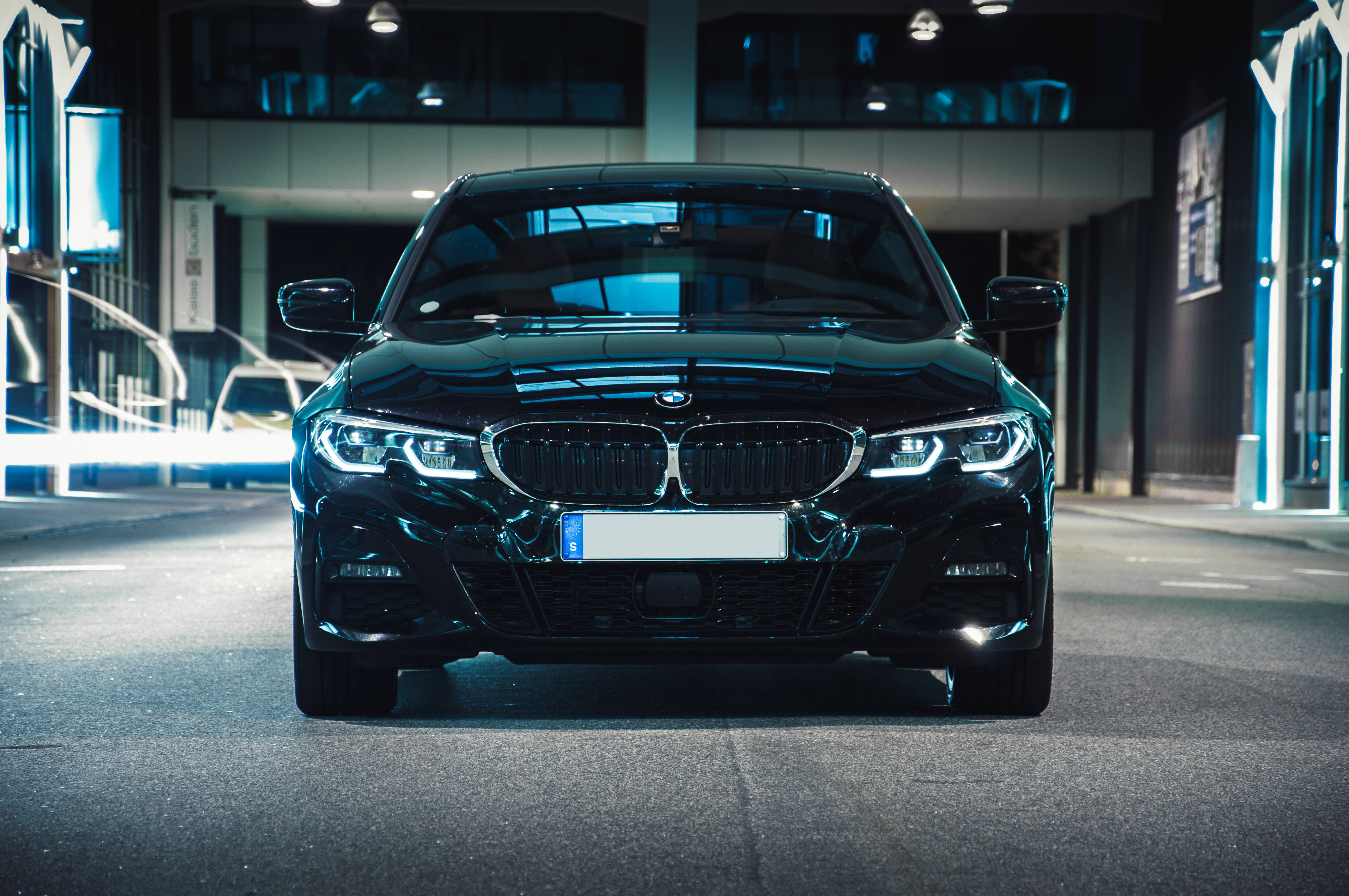 黑色寶馬車頭特寫 壁紙 — 一輛時尚的黑色BMW轎車在現代都市夜晚的霓虹燈下閃耀。