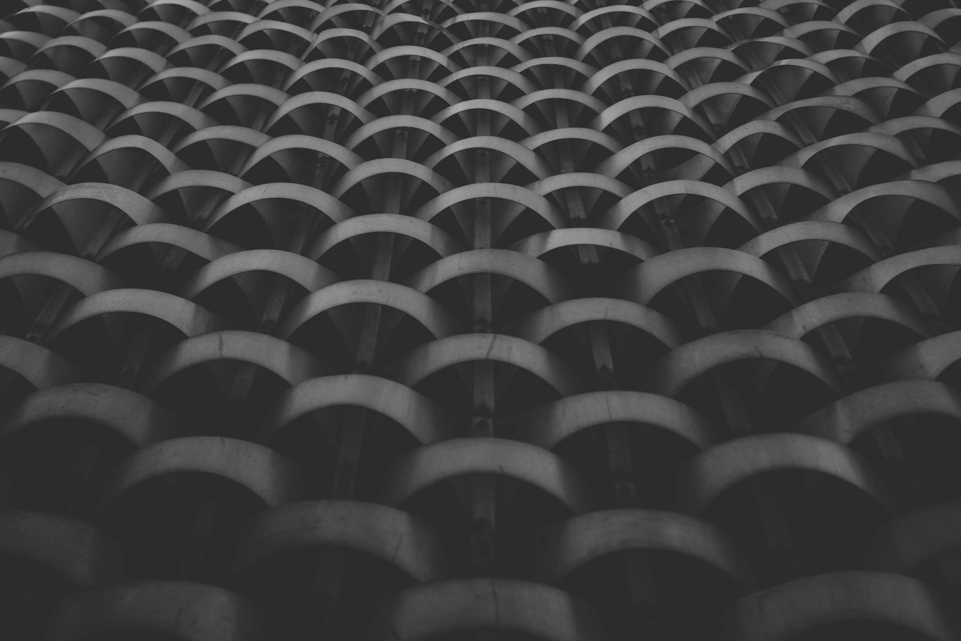 單色重複彎曲建築圖案，帶有強烈陰影。