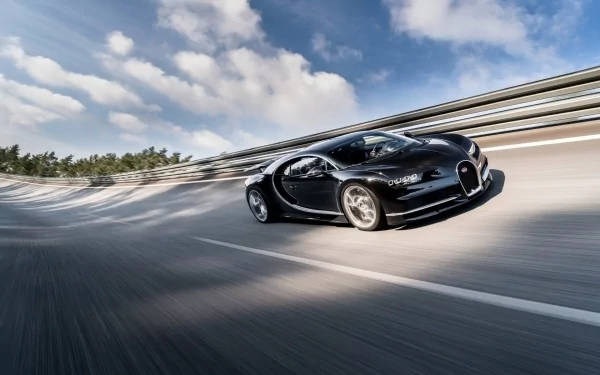 黑色Bugatti Chiron在陽光明媚的天空下在彎曲的道路上飛馳。