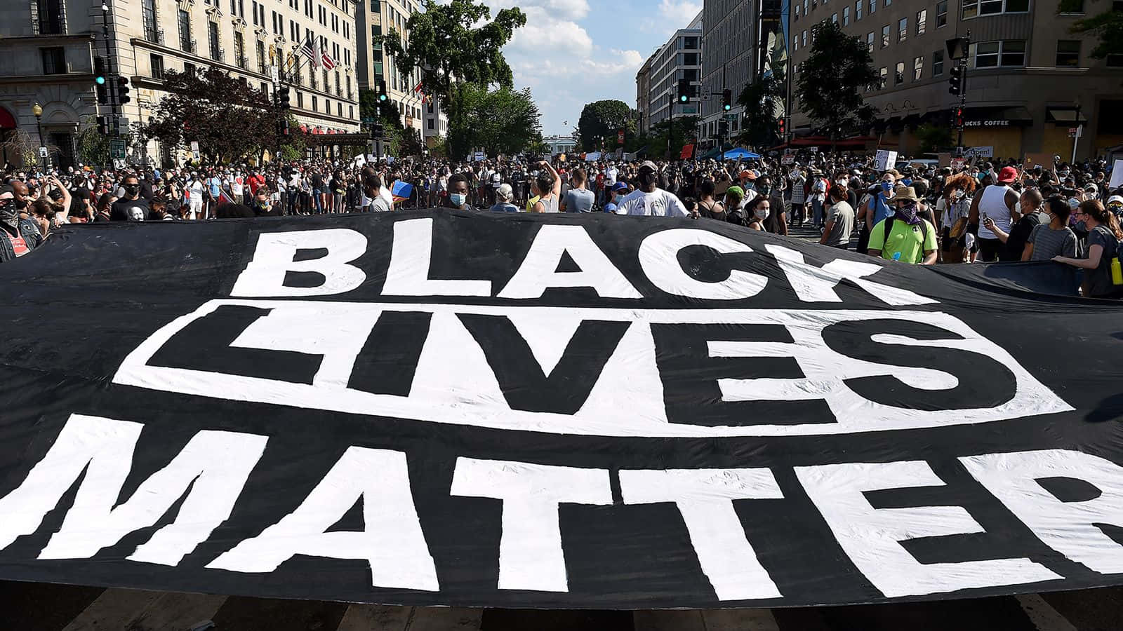 抗議者在日間示威期間，帶著一面大型 Black Lives Matter 橫幅穿過城市街道。