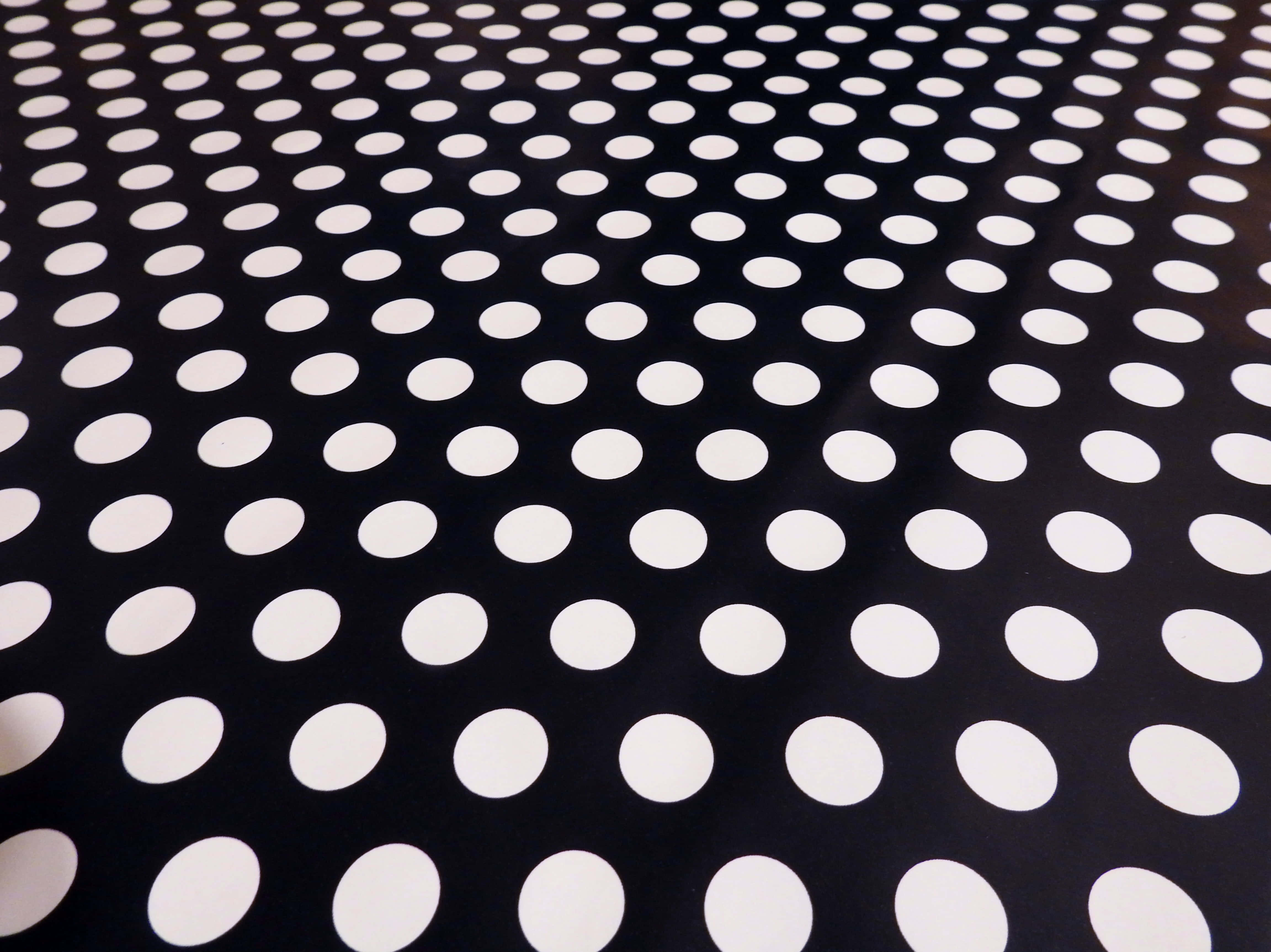Black And White Dots 桌布 壁紙 — 黑色布料嘅特寫，上面有均勻分佈嘅白色波點，形成大膽嘅幾何圖案。