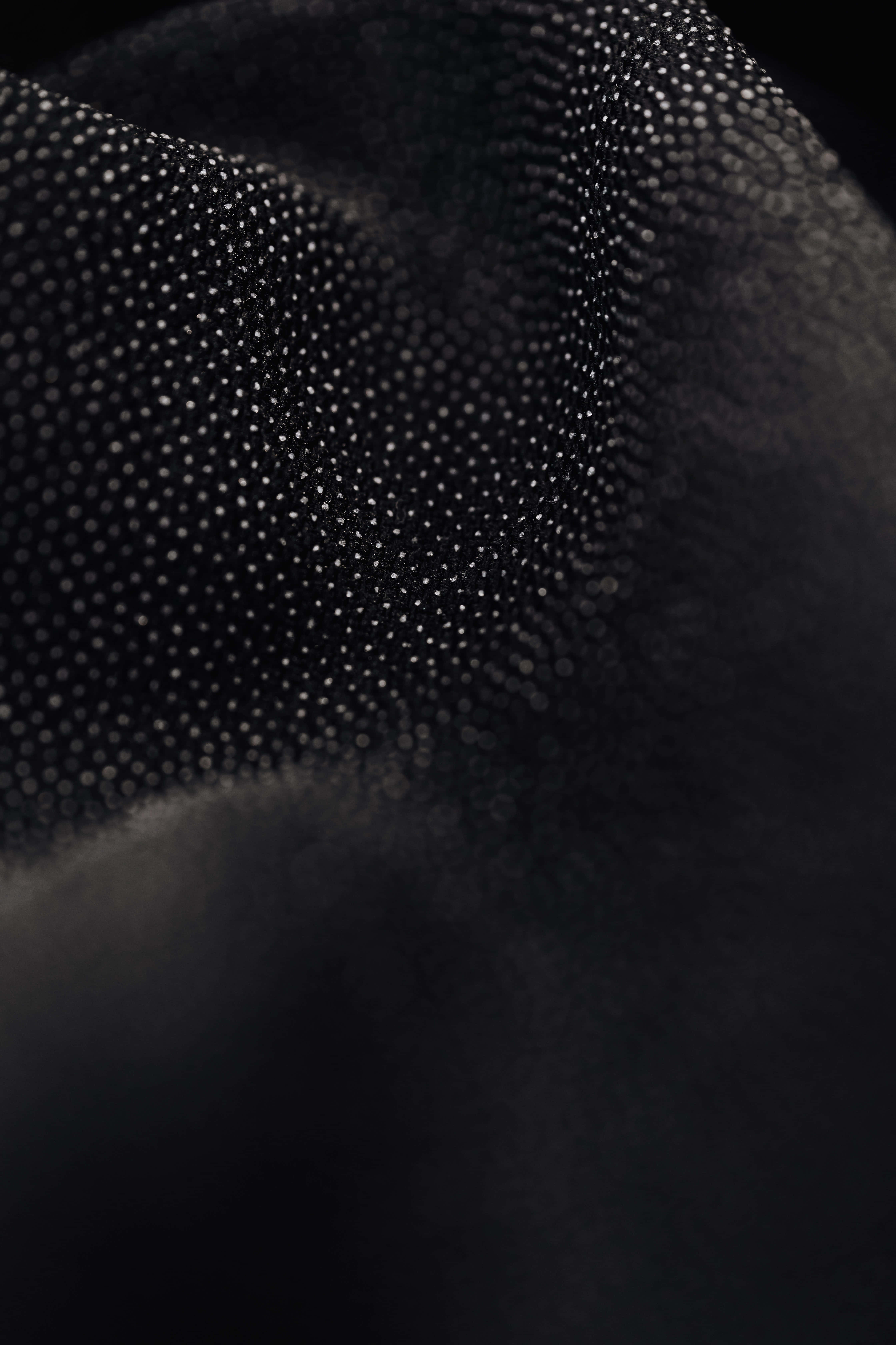 Black And White Dots 桌布 壁紙 — 黑色布料嘅特寫，帶有圓點紋理，柔和嘅光線突顯其複雜圖案同深度。
