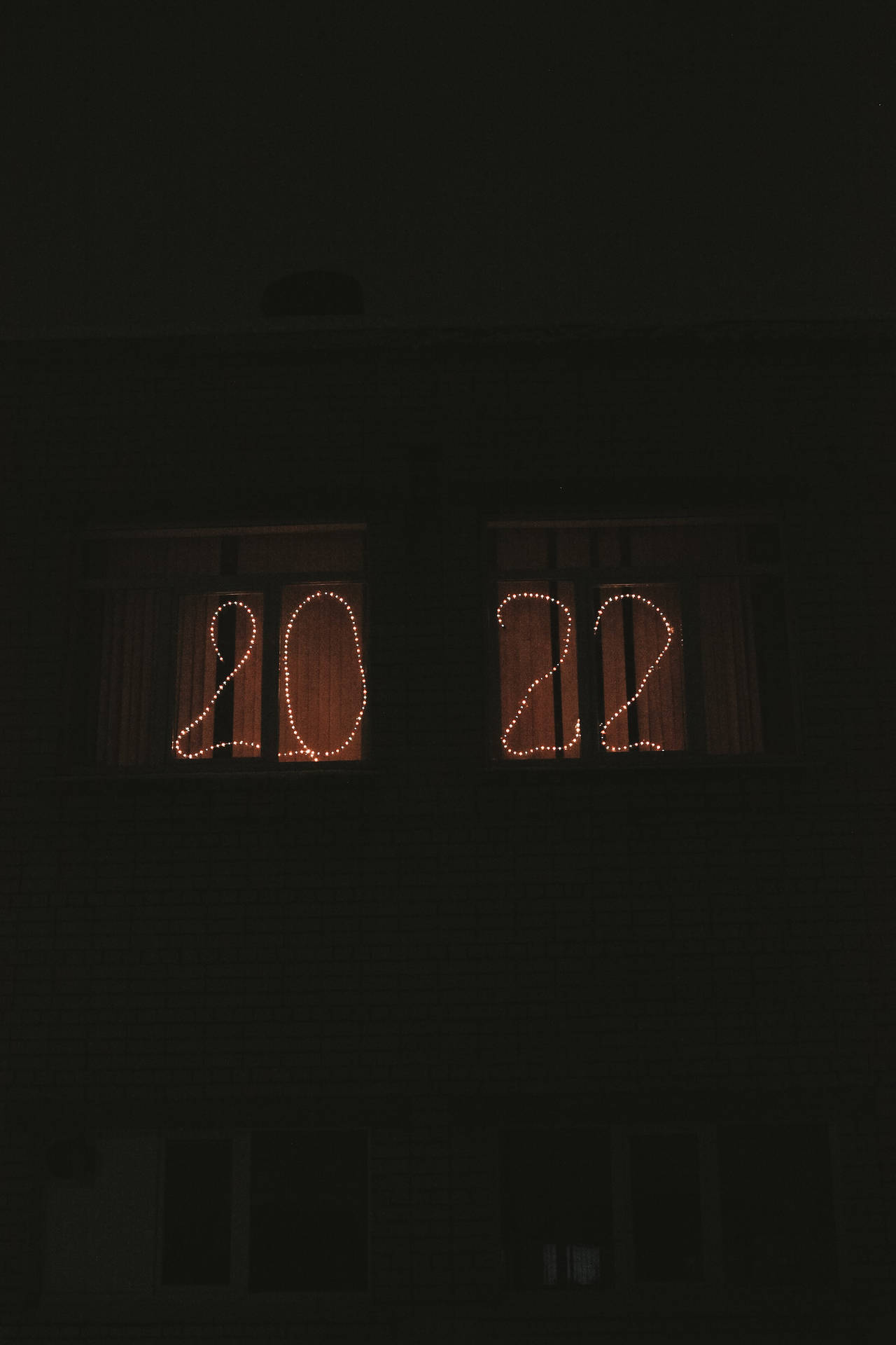 串燈在夜間黑暗建築物的窗戶中形成2022年。