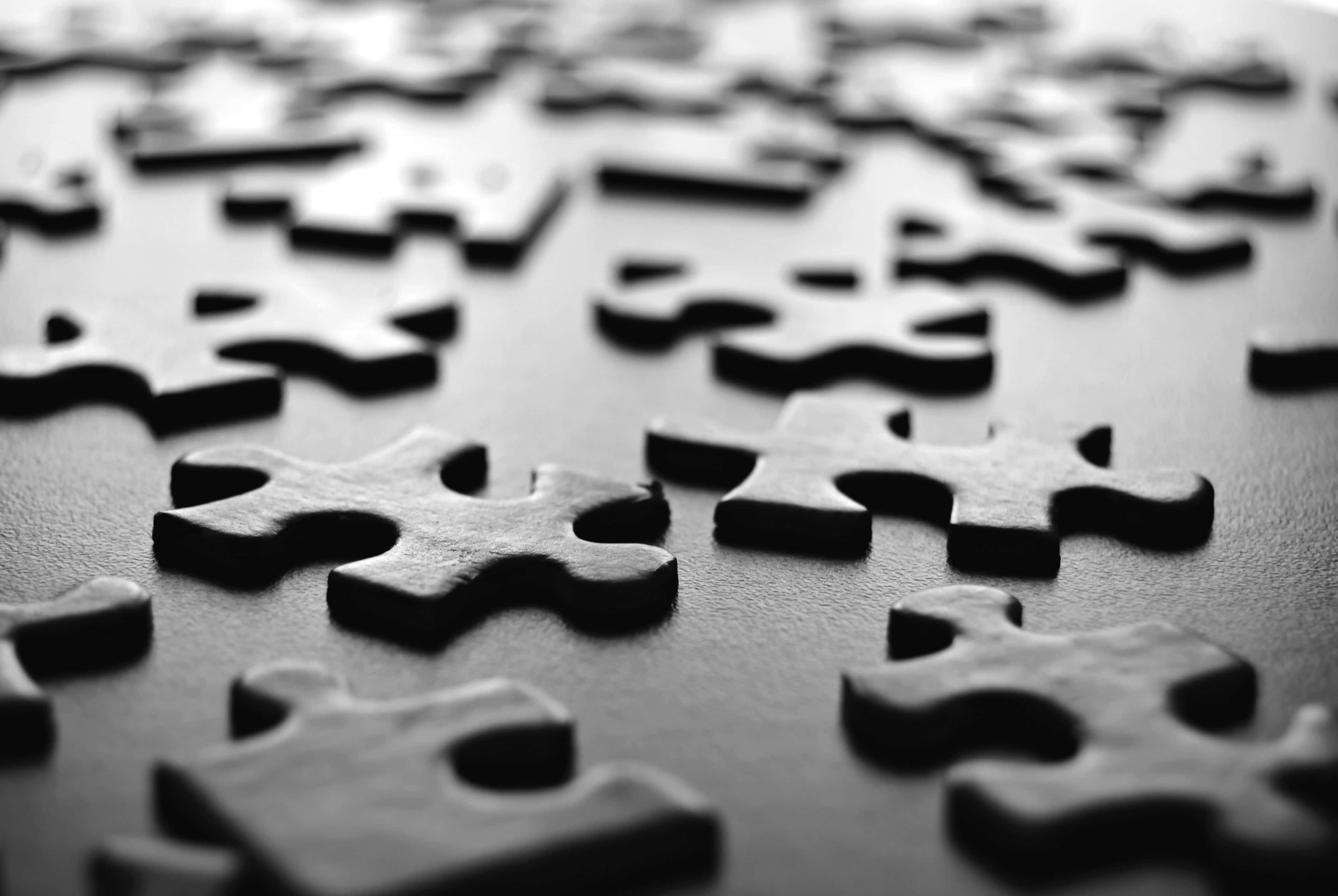 Puzzle Games 桌布 壁紙 — 黑色拼圖碎片散落在深色表面上的特寫，淺景深。