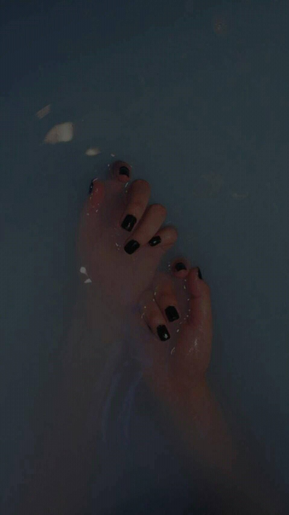 黑色指甲油暗黑龐克美學 壁紙 — 一隻塗了黑色指甲油的手輕輕浸在深色水中，有漂浮的白色花瓣。