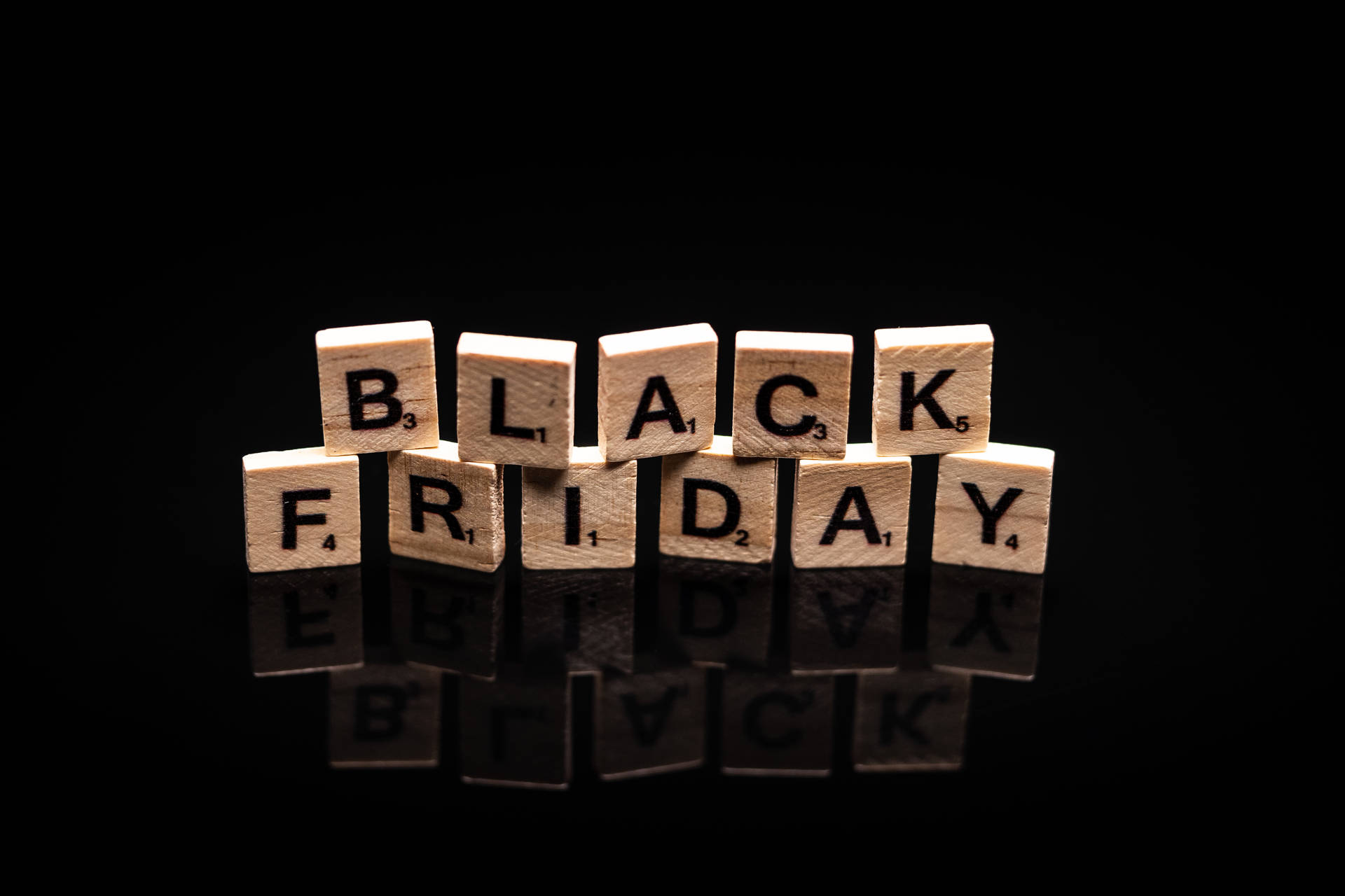 黑色反光表面上用木製Scrabble字母牌拼出的Black Friday。