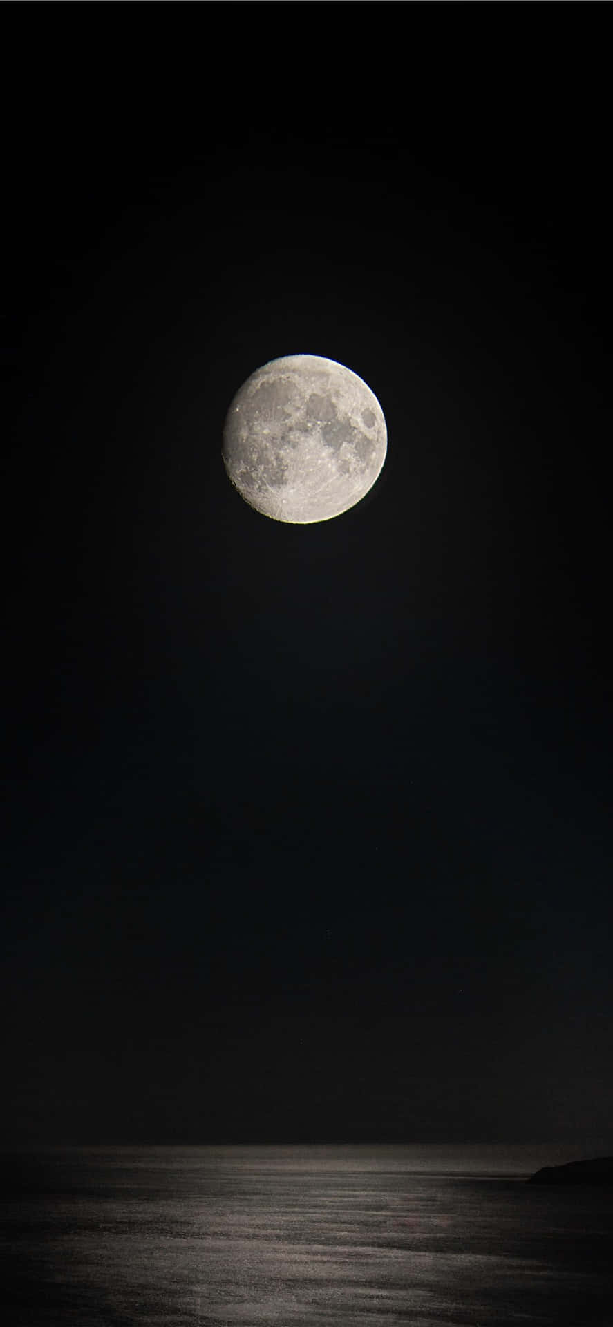 黑色月亮 iPhone 版 壁紙 — 一輪明亮的滿月高掛在平靜的海洋之上，背景是深邃的黑色夜空。