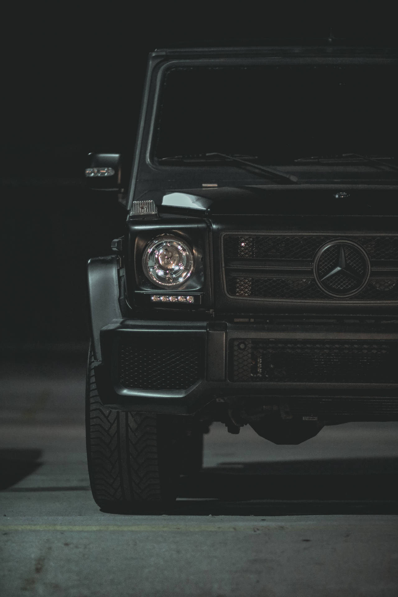 黑色 Mercedes G-Wagen 夜間停車，車頭燈亮起。
