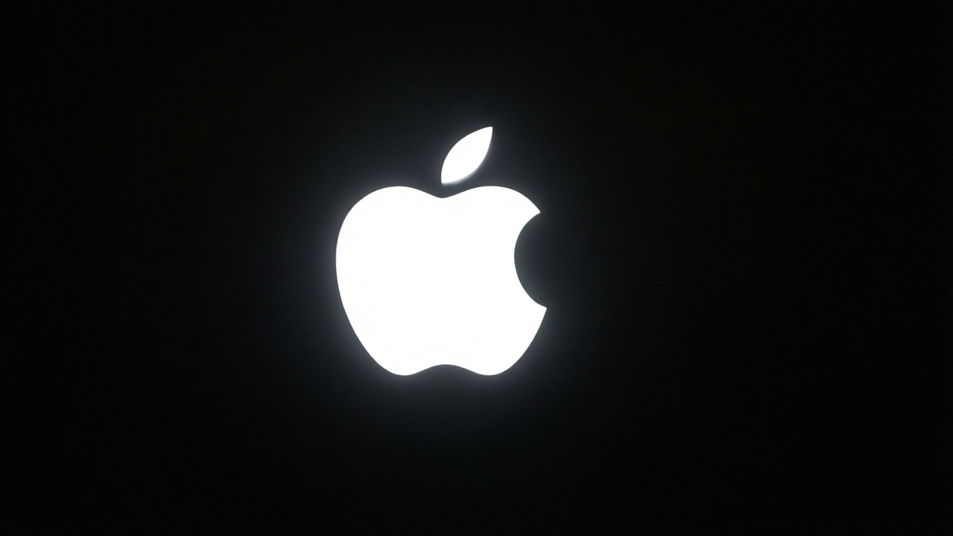 黑色極簡光效 壁紙 — 發光的白色Apple標誌在純黑色背景上顯得格外突出。