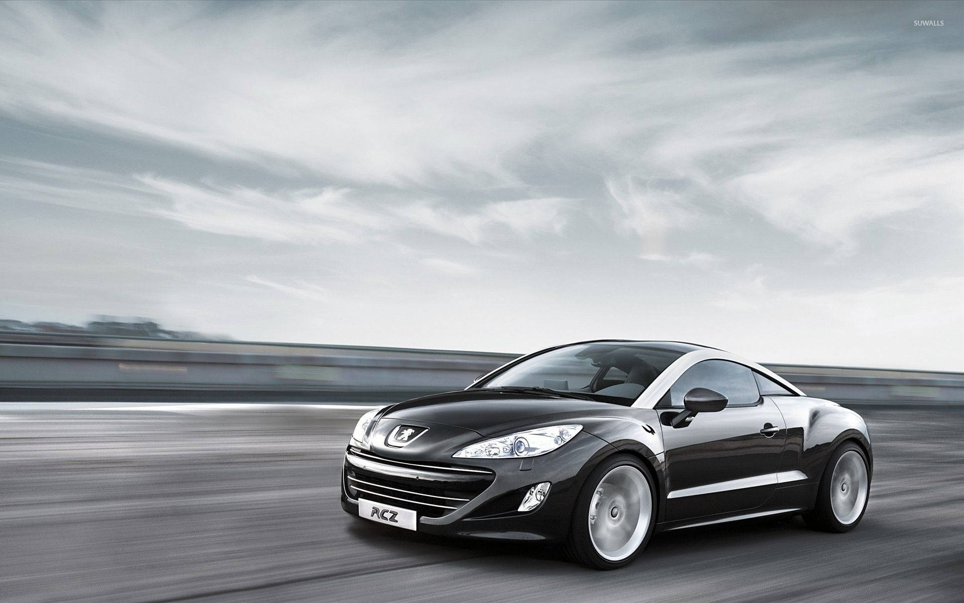 黑色Peugeot RCZ跑車在高速公路上飛馳，帶有動態模糊效果。
