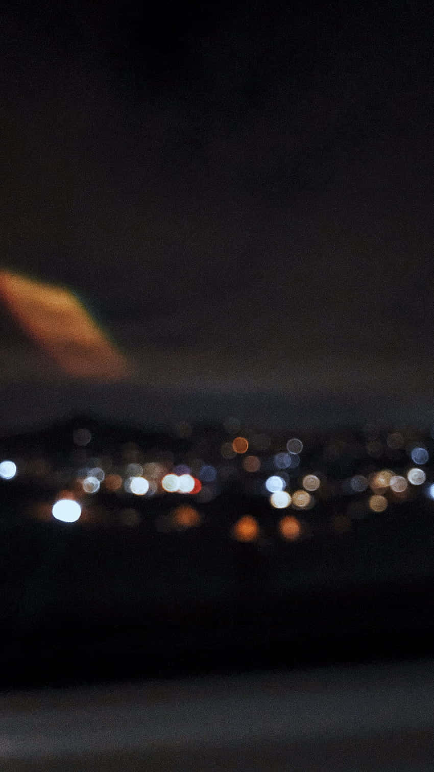 夜間城市燈光模糊成發光球體，天空中有溫暖的條紋。