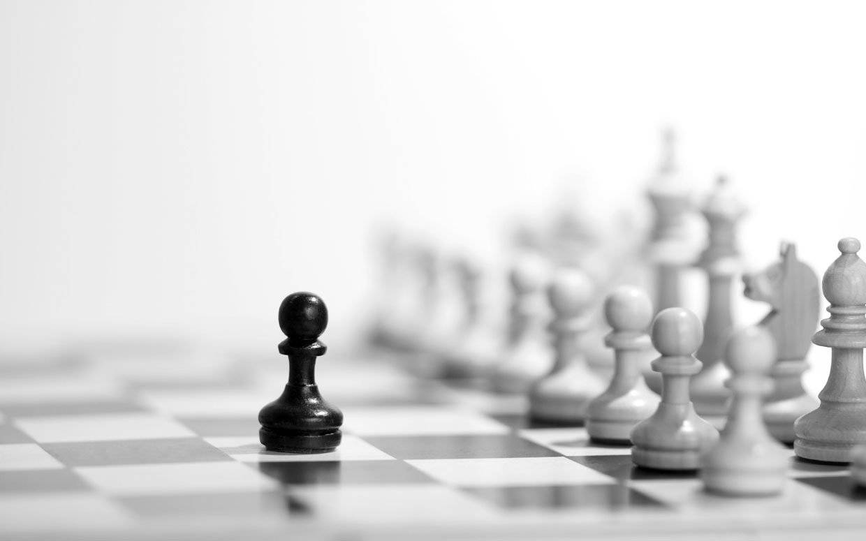 黑色無畏兵 壁紙 — 一個黑色國際象棋兵卒在棋盤上清晰對焦，背景中模糊的白色棋子軍隊排列成行。