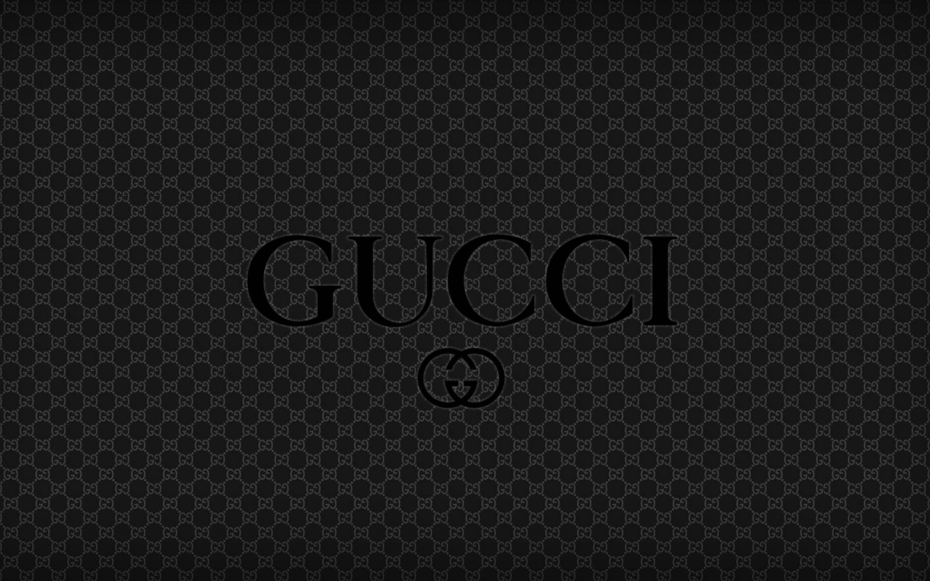 Gucci 桌布 壁紙 — 黑色牆紙，Gucci 標誌居中置於重複的灰色單字母圖案之上。