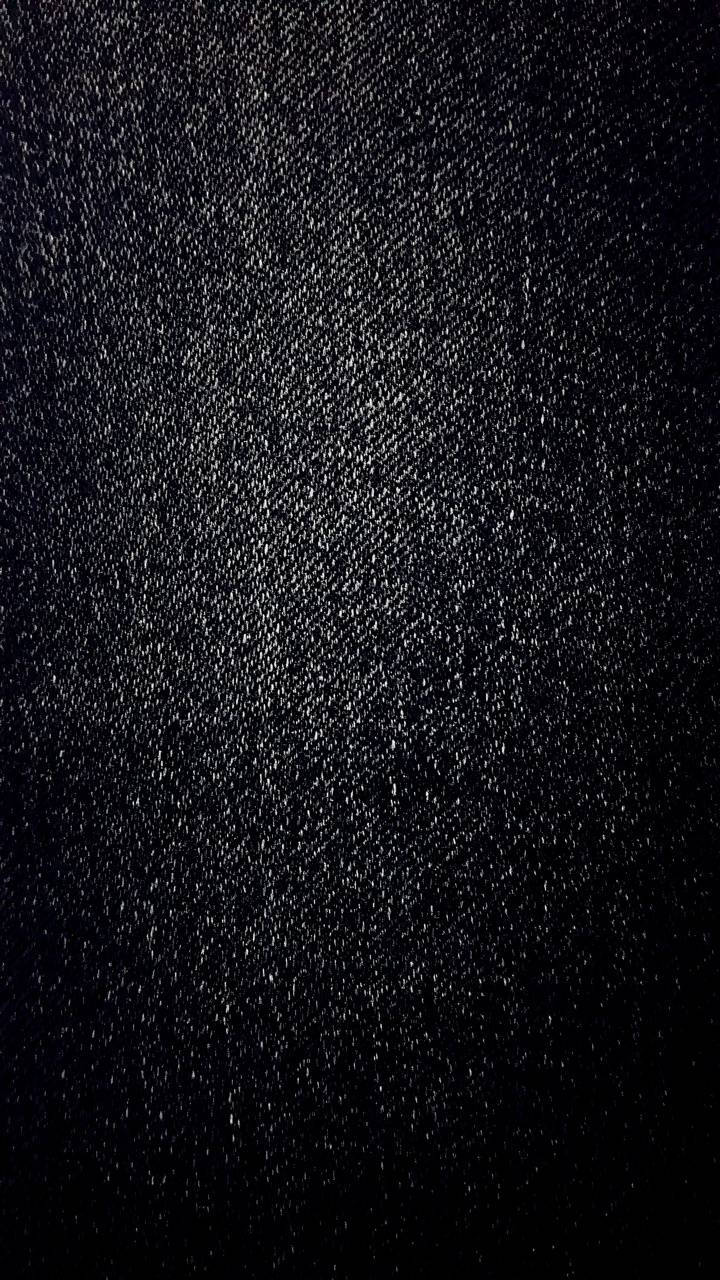 黑色牛仔布料紋理 壁紙 — 深色牛仔布料的特寫，帶有細微的白色斑點和斜紋編織質感，在柔和光線下呈現。