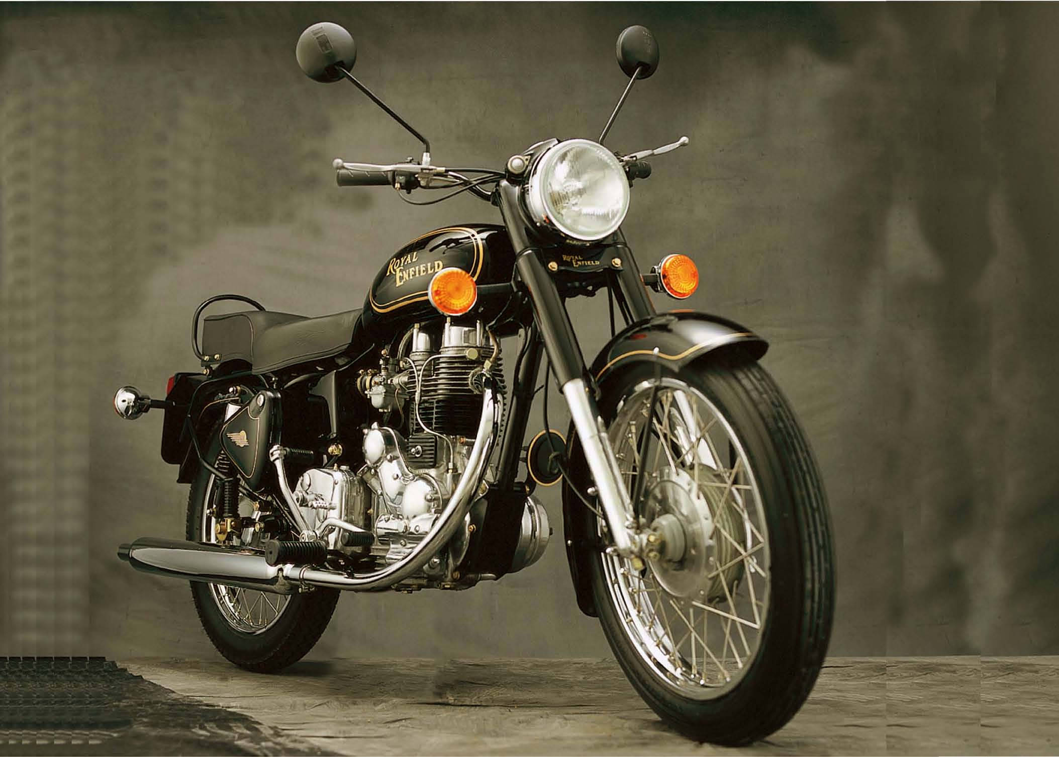 黑色皇家恩菲德高畫質灰底 壁紙 — 一輛經典的Royal Enfield電單車，帶有鍍鉻裝飾和橙色指揮燈，在柔和的灰色工作室背景前蓄勢待發。