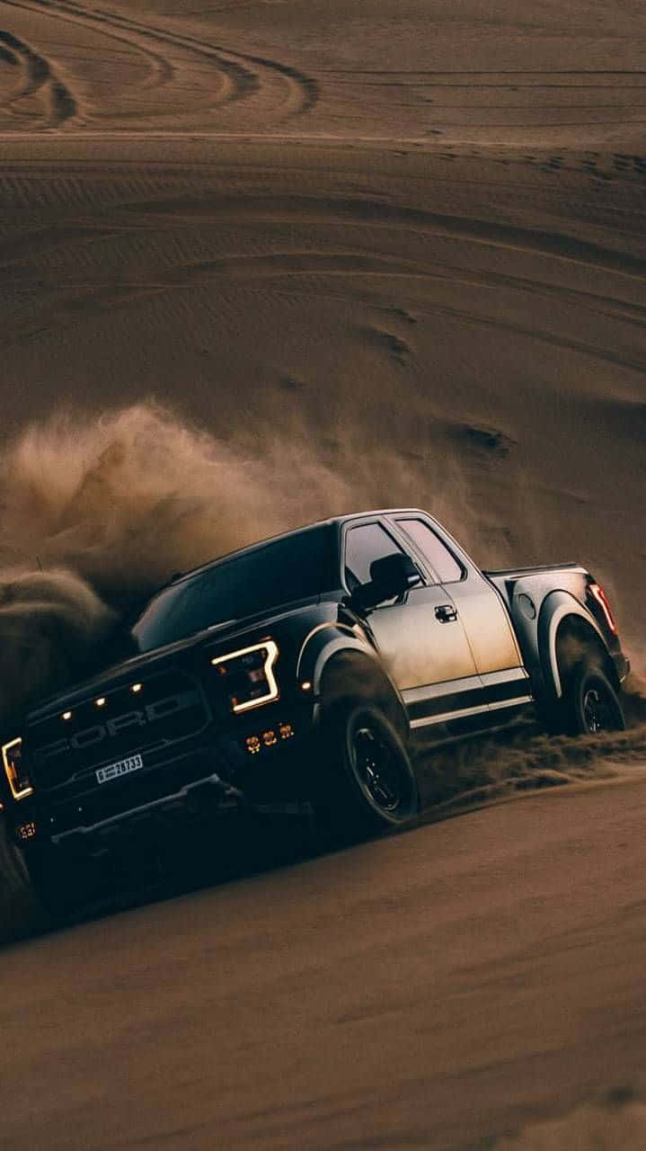 黑色福特F-1500皮卡攝影 壁紙 — 黑色福特 F-150 Raptor 在沙漠沙丘上高速飛馳，揚起沙塵，低角度拍攝充滿戲劇性。