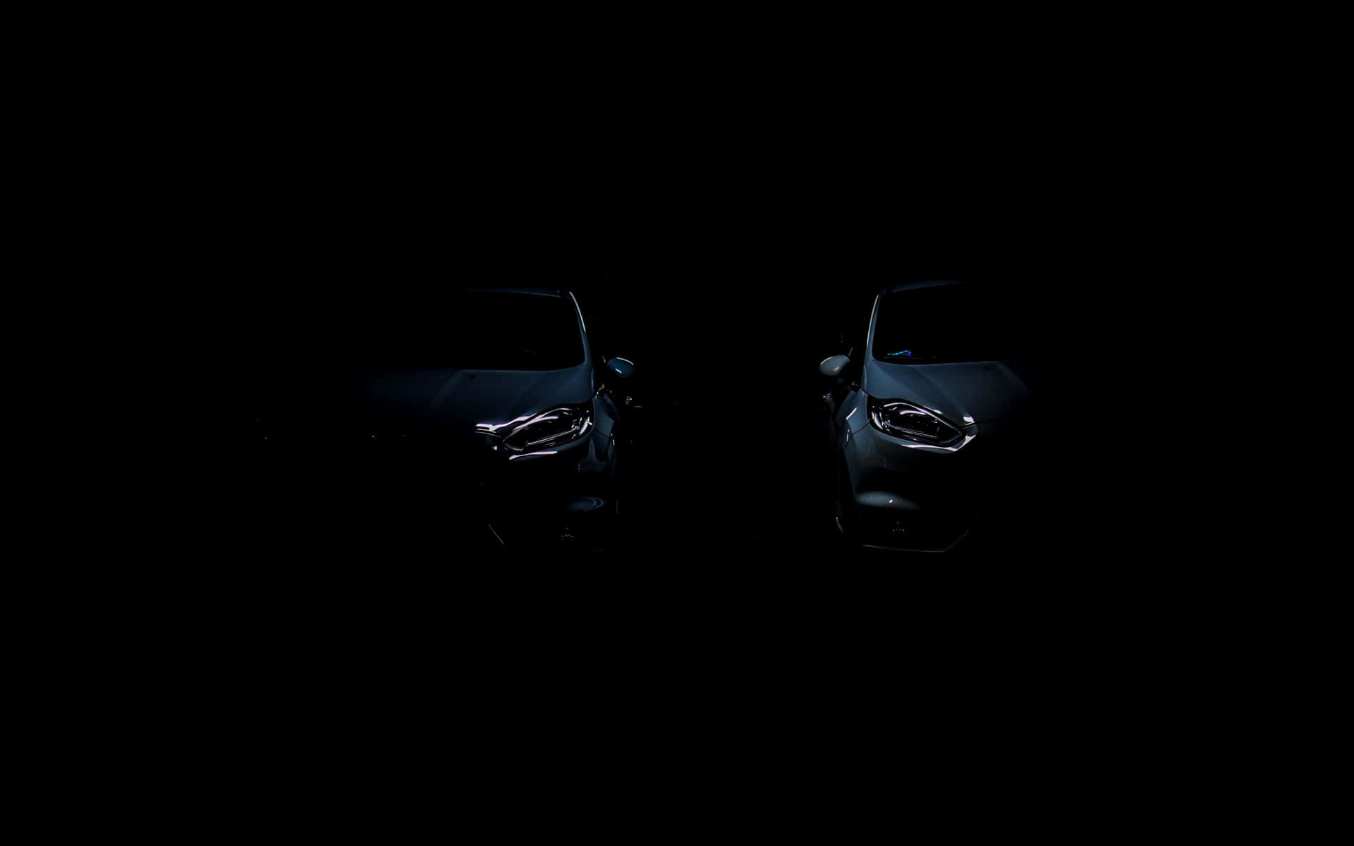 兩輛在完全黑暗中帶有發光車頭燈的汽車。