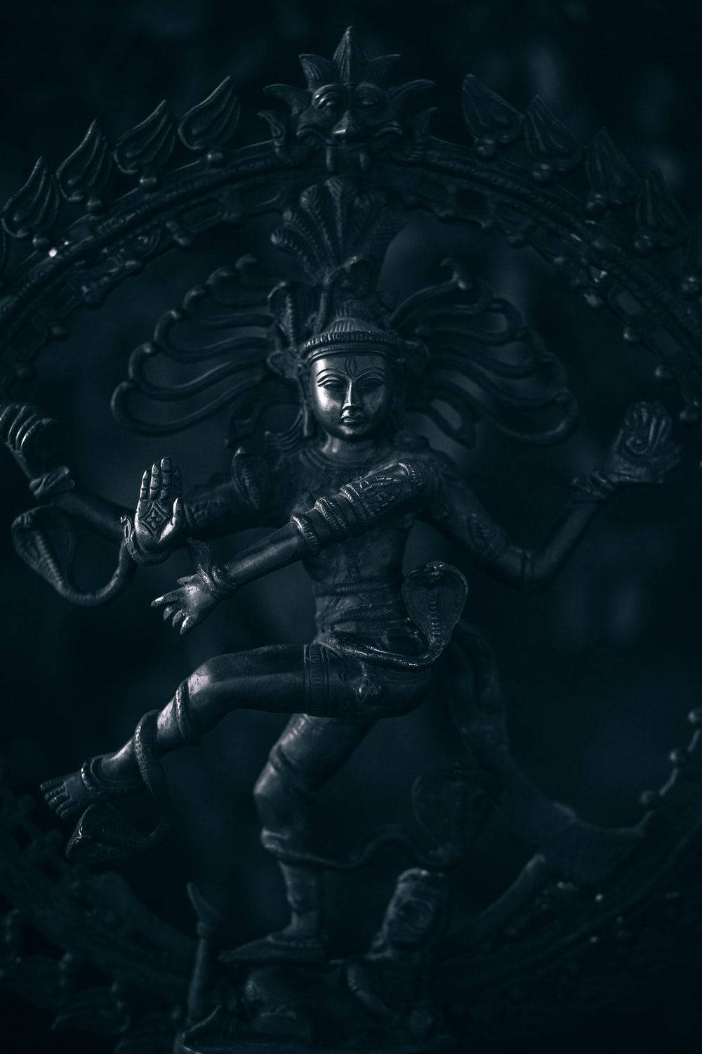 一尊深色的多臂神祇在圓形光環中跳舞的雕像。