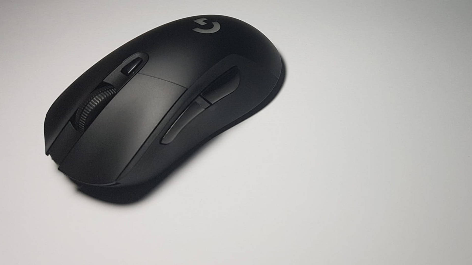 黑色羅技滑鼠 壁紙 — 一款時尚的黑色Logitech遊戲滑鼠放置在帶有柔和陰影的純白表面上。
