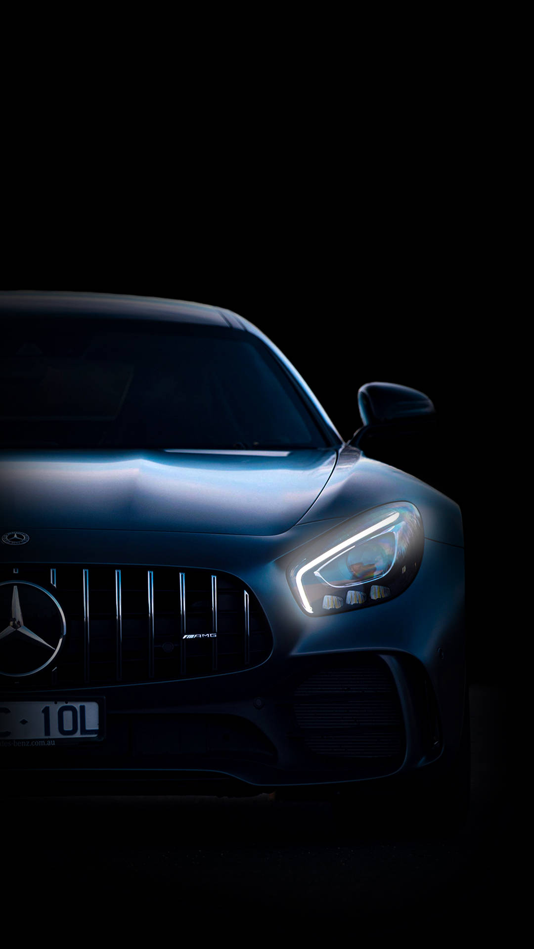 在黑暗中閃爍車頭燈的時尚藍色 Mercedes-AMG 跑車。