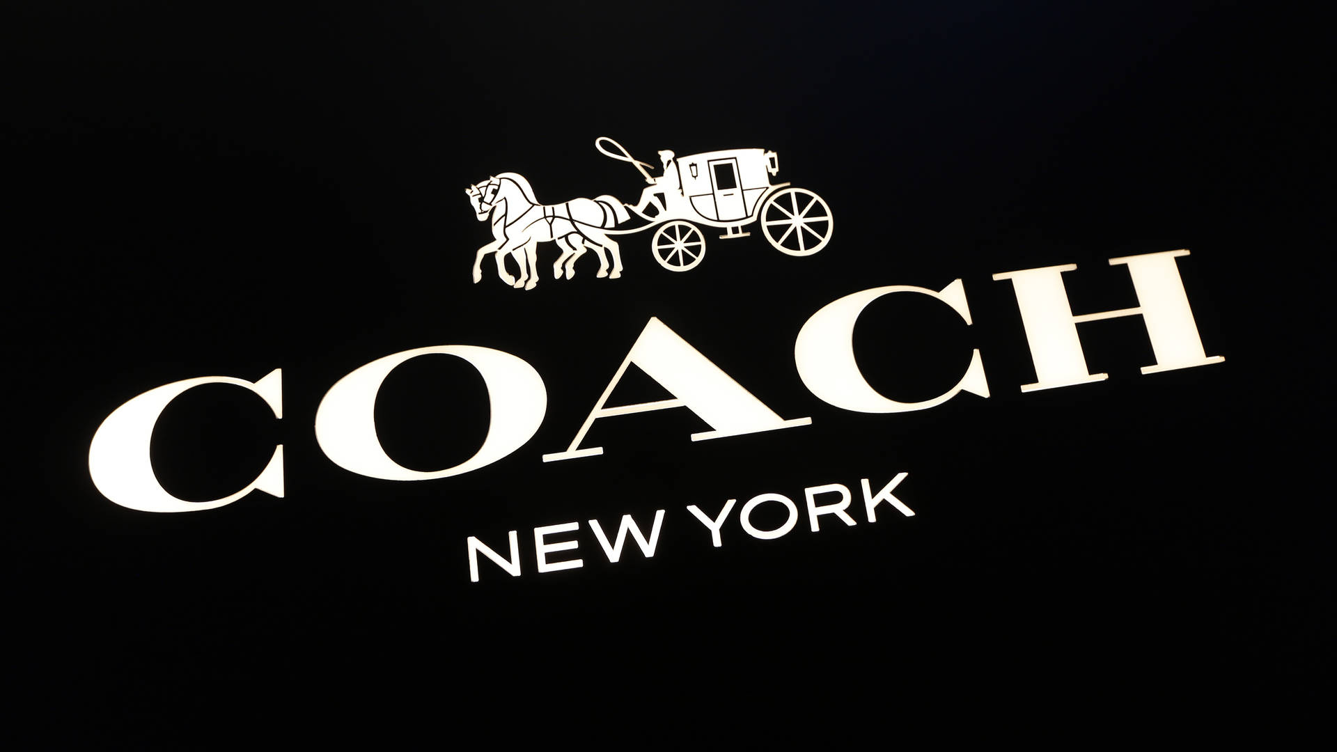 黑色背景上的Coach New York標誌，帶有馬和馬車