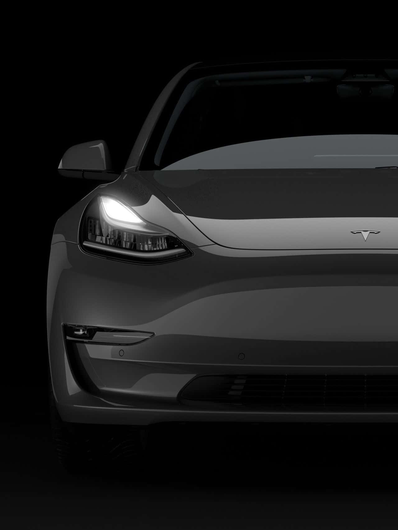 tesla 桌布 壁紙 — 黑色背景上，一輛時尚灰色Tesla汽車的前視圖，帶有發光的車頭燈。