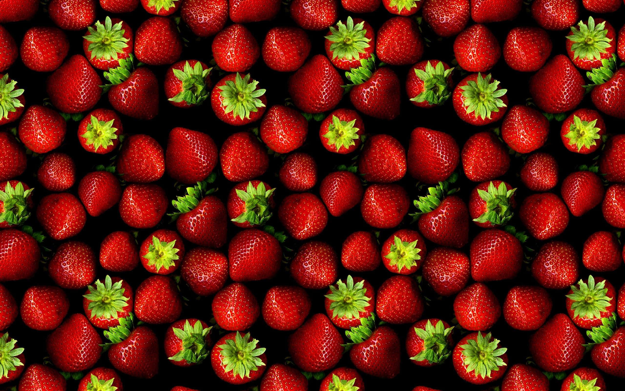 Red Strawberry 桌布 壁紙 — 黑色背景上，鮮紅色士多啤梨與綠色頂部緊密特寫。