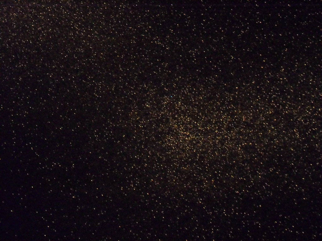 充滿金色閃粉粒子嘅深色背景。