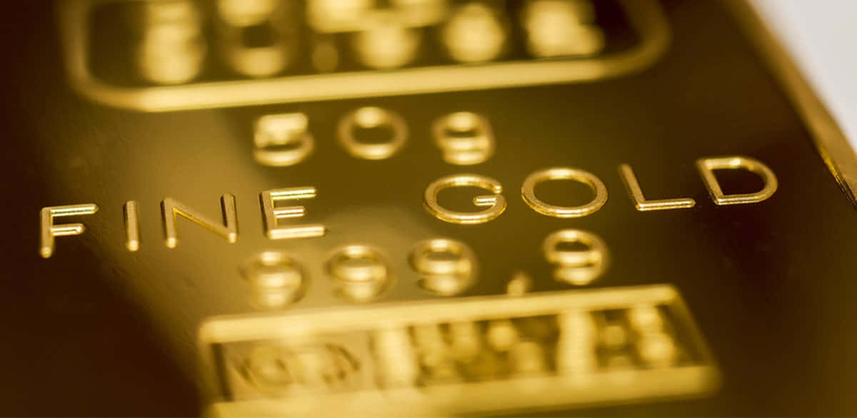黑色背景上的金條堆疊 壁紙 — 喺溫暖燈光下，閃閃發光嘅金條上面刻有「FINE GOLD 999.9」字樣嘅特寫。