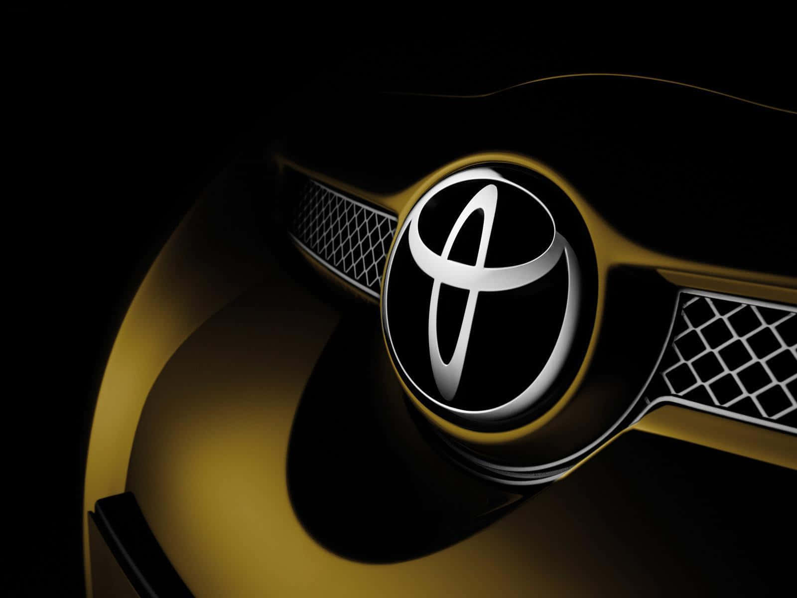 Toyota 桌布 壁紙 — 黑色背景上金色汽車格柵中央閃亮銀色豐田標誌的特寫。