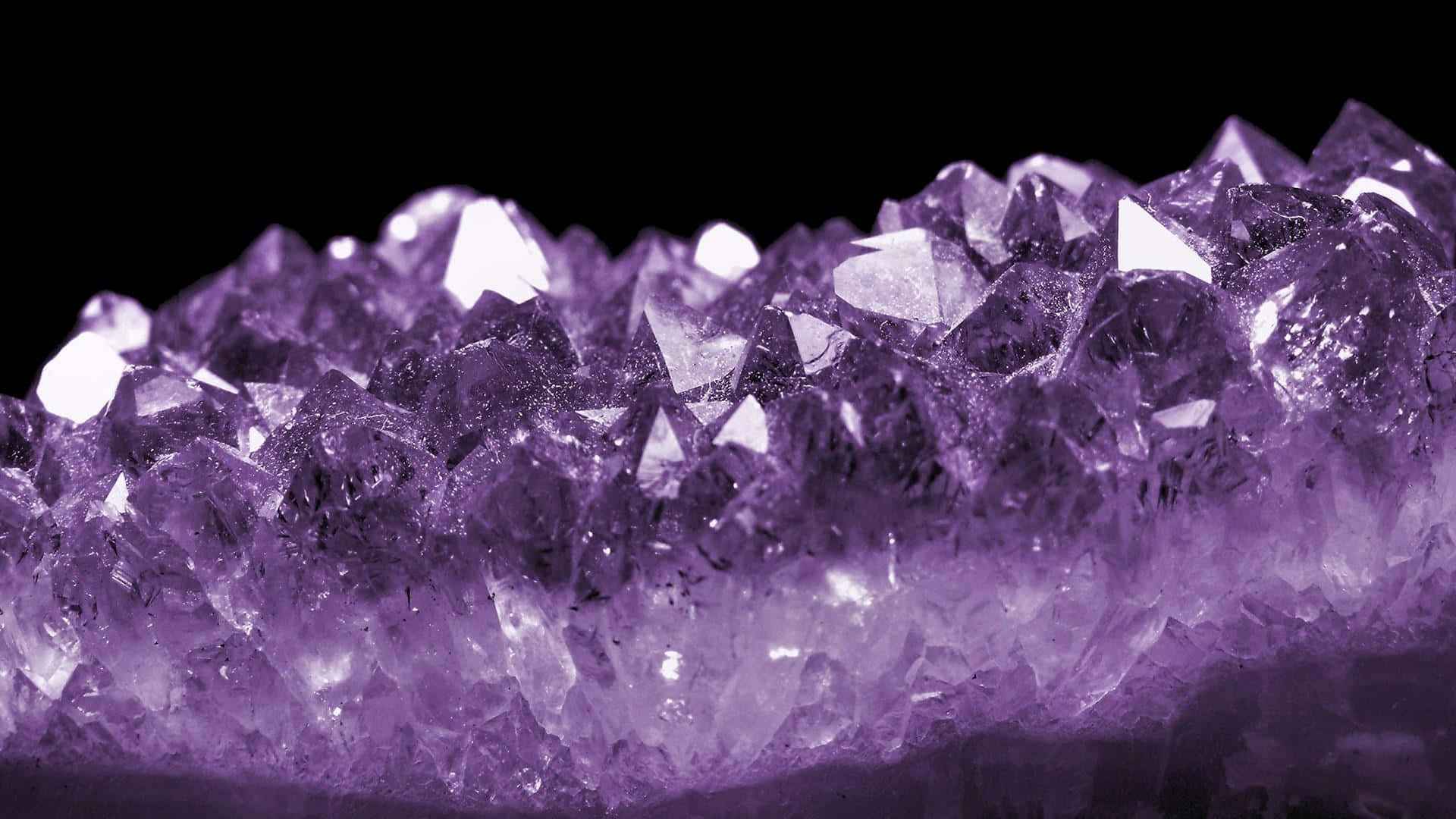 Amethyst 桌布 壁紙 — 黑色背景上閃閃發光的紫色紫水晶晶體的近距離特寫。