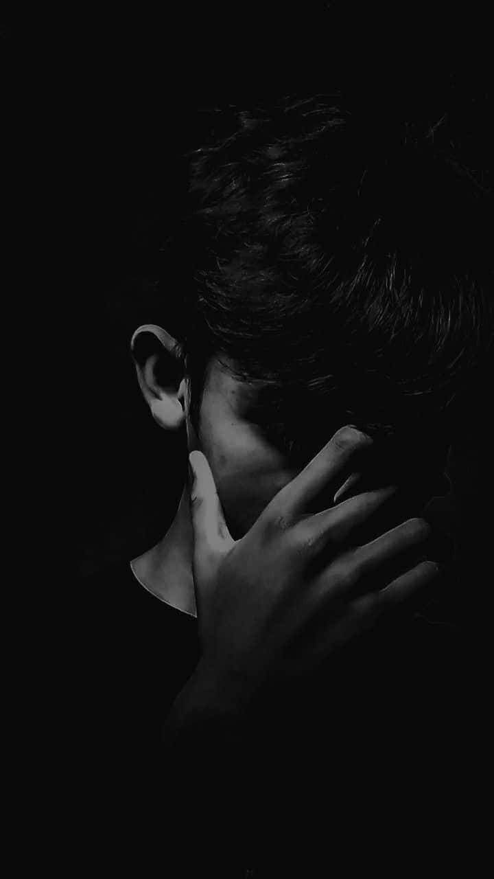黑色背景下的悲傷男子照片 壁紙 — 一個黑白的人用一隻手遮住臉，背景是深色。