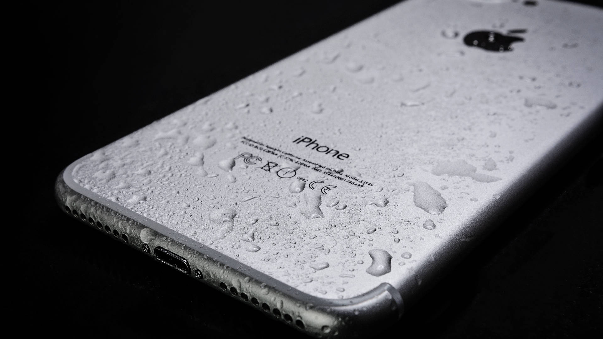 黑色背景上背面帶有水滴的銀色 iPhone。