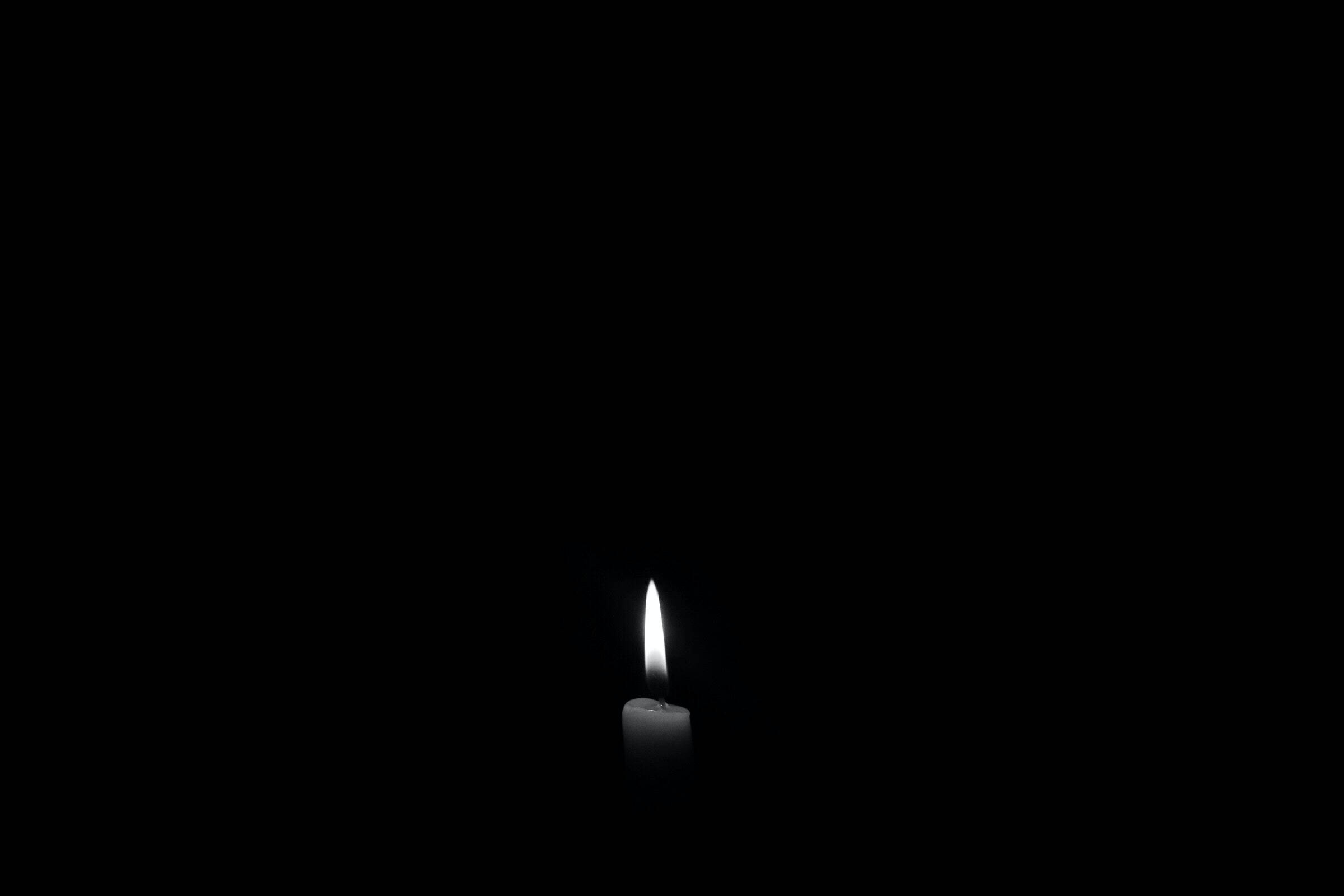 黑色背景燭光 壁紙 — 一根白色蠟燭在漆黑背景中明亮燃燒，投射出柔和的光芒。