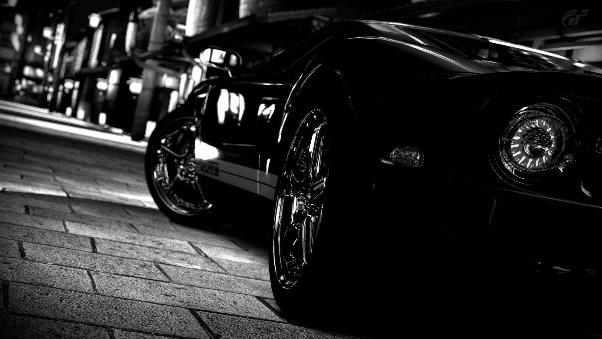黑色跑車在夜間停放在鵝卵石街道上，帶有戲劇性的燈光。