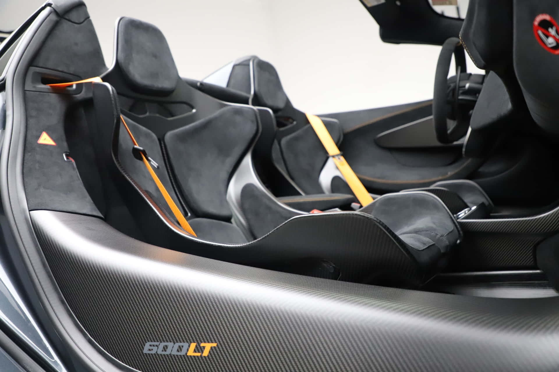 Mclaren 600lt Spider 桌布 壁紙 — 黑色跑車內飾特寫，採用碳纖維飾邊和鮮艷的橙色安全帶。