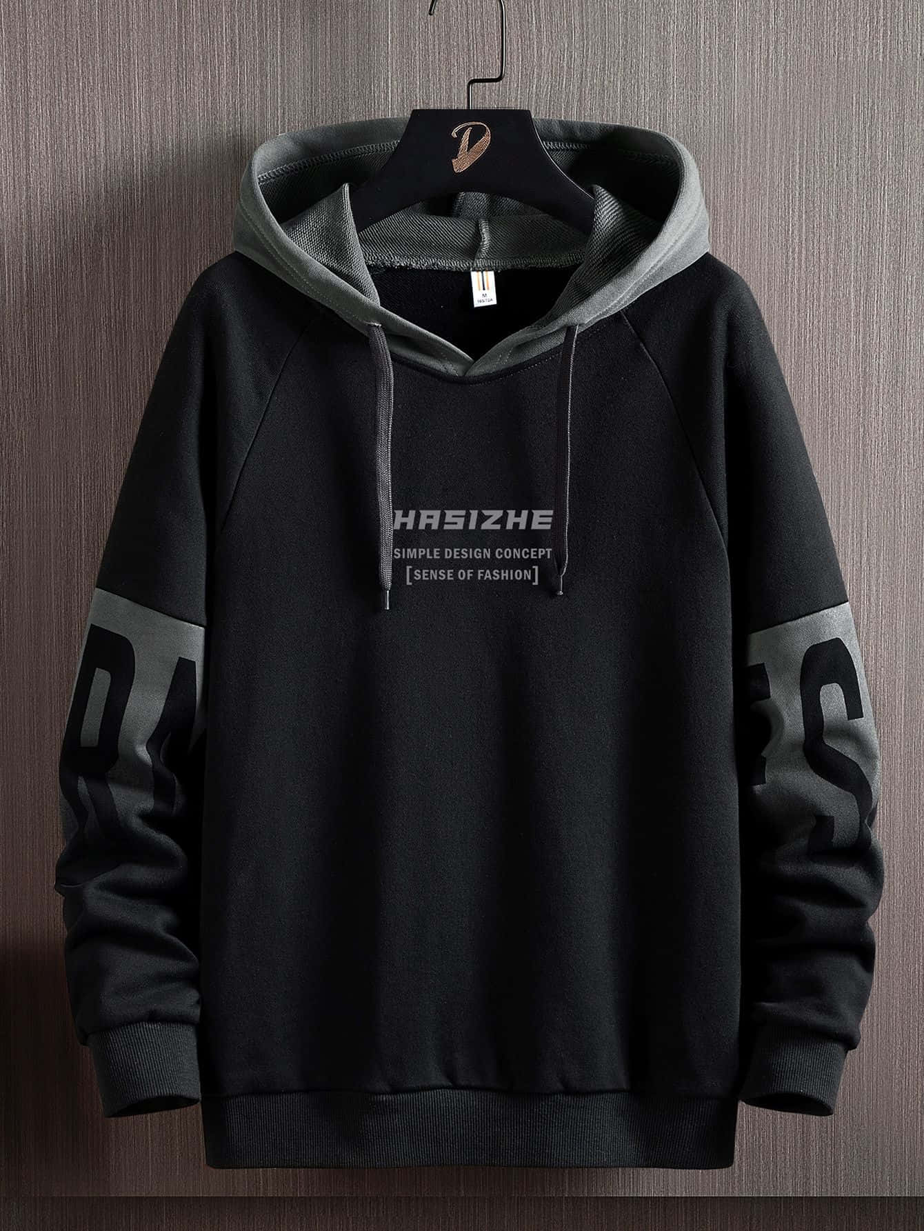 Black Clothing 桌布 壁紙 — 黑色連帽衛衣，帶灰色點綴和粗體袖口文字，掛在衣架上，背景為木牆。
