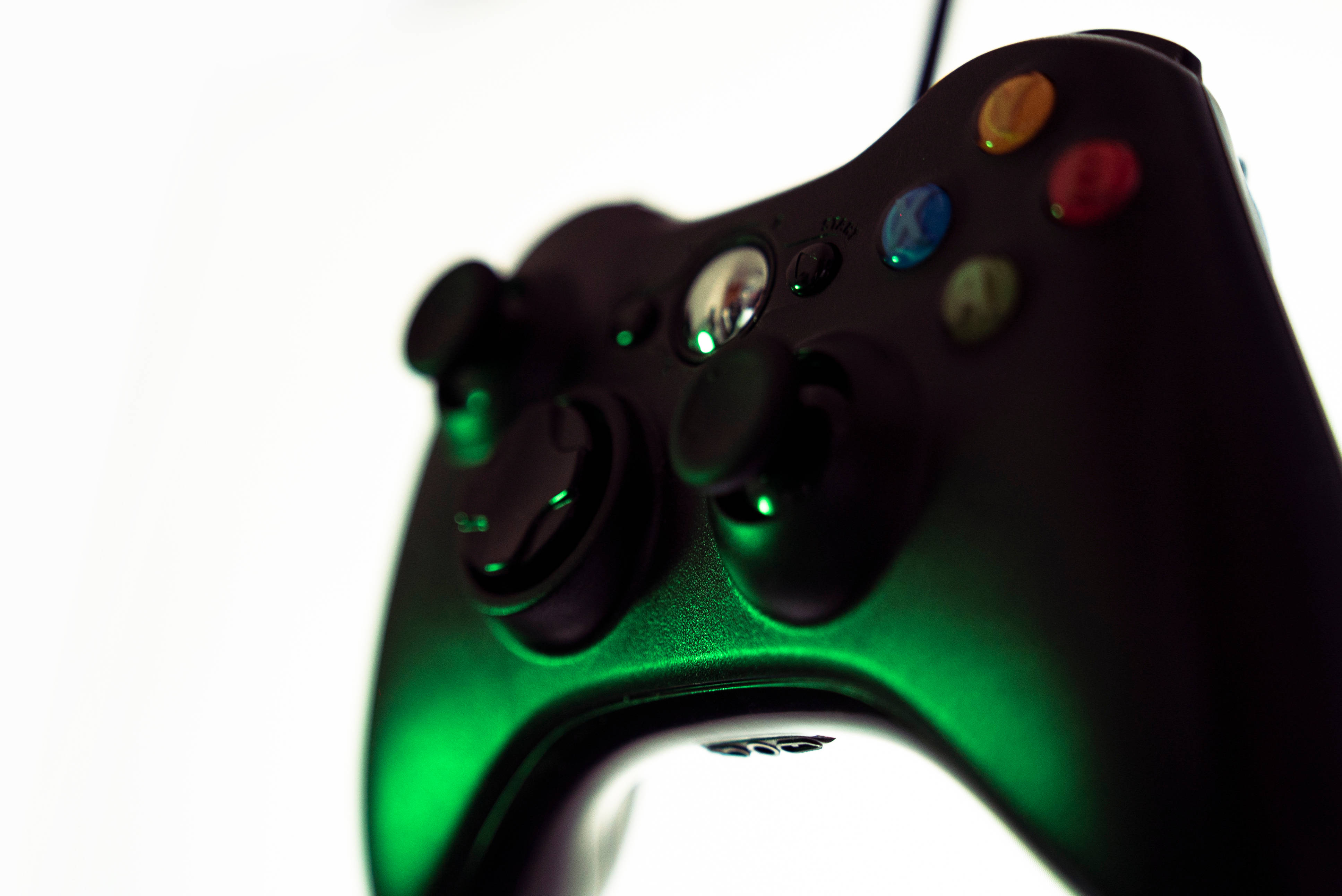 黑色遊戲搖桿 壁紙 — 黑色Xbox手掣在純白背景上發出鮮豔綠光的特寫。