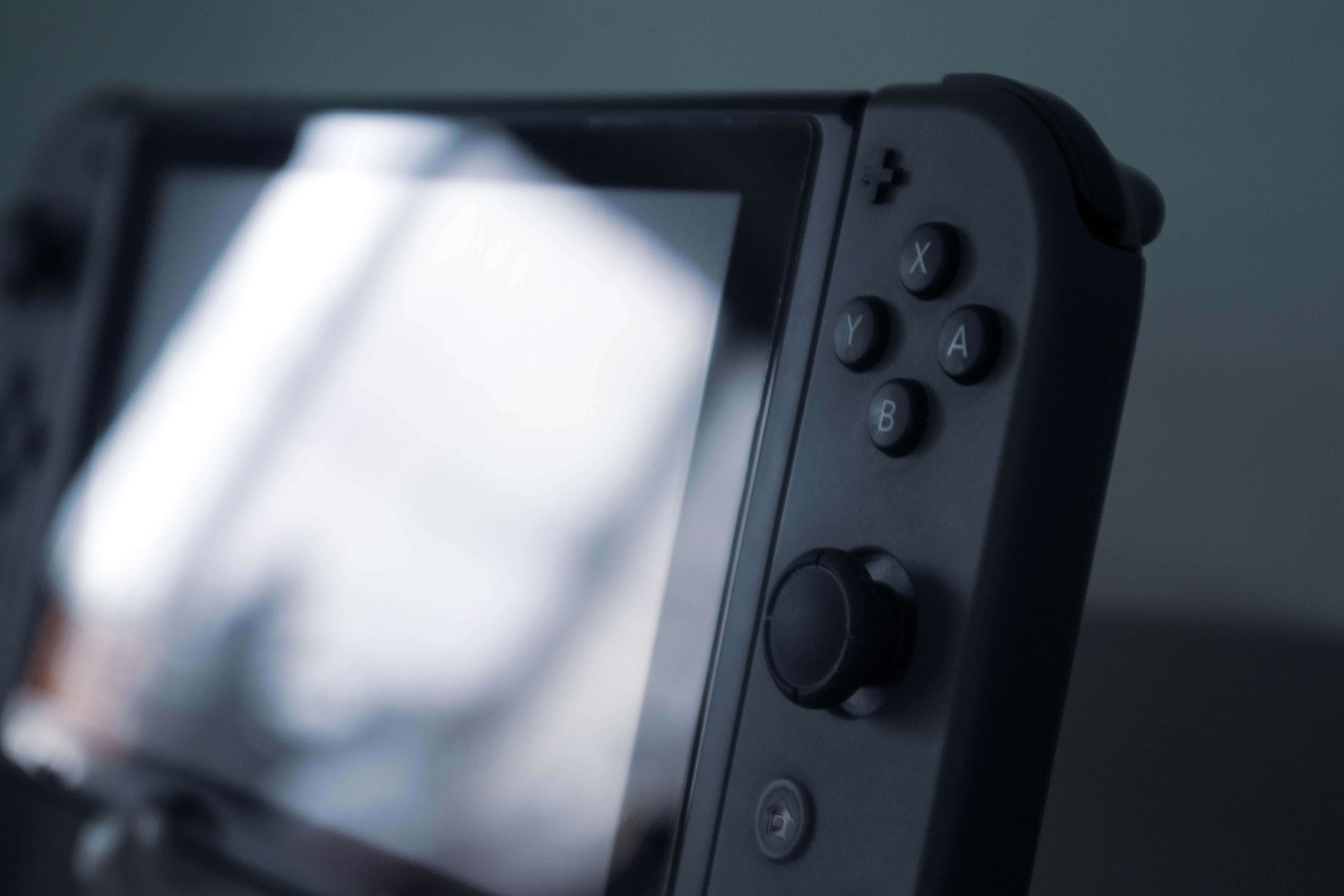 Gaming Consoles 桌布 壁紙 — 黑色遊戲機手掣的特寫，帶有按鈕和屏幕，柔焦效果。