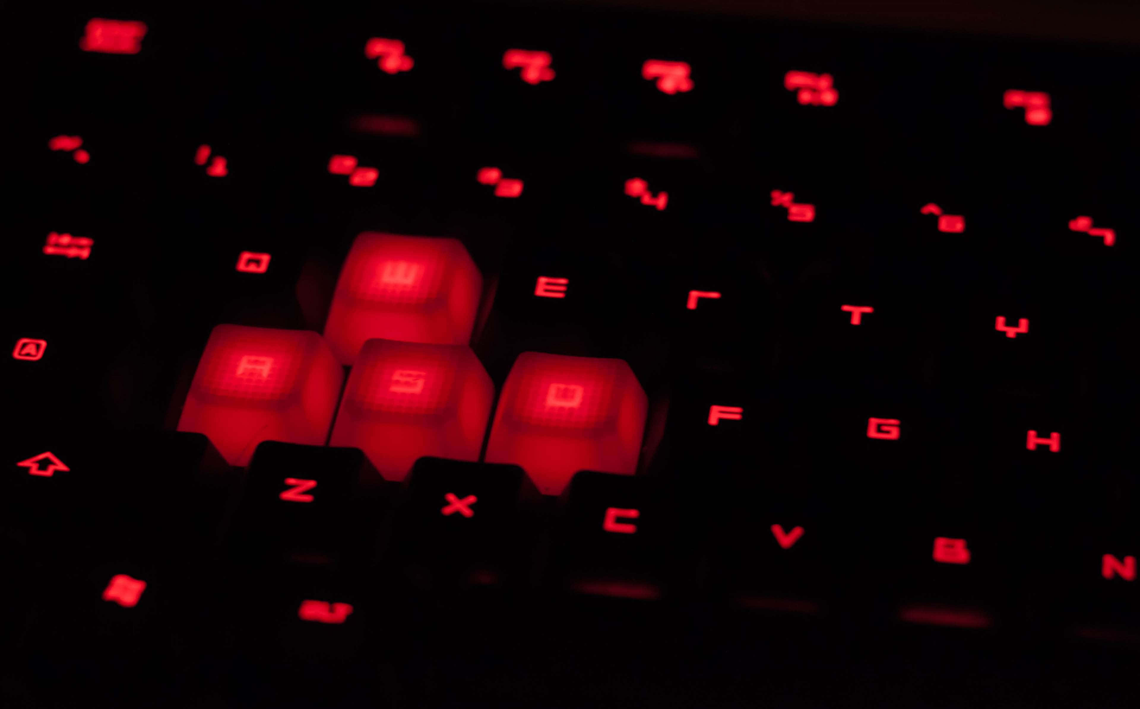 Gaming Keyboards 桌布 壁紙 — 黑色鍵盤在黑暗中發出鮮豔紅色背光的特寫。